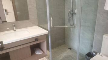 A bathroom with a glass-enclosed shower, a sink, and a toilet.