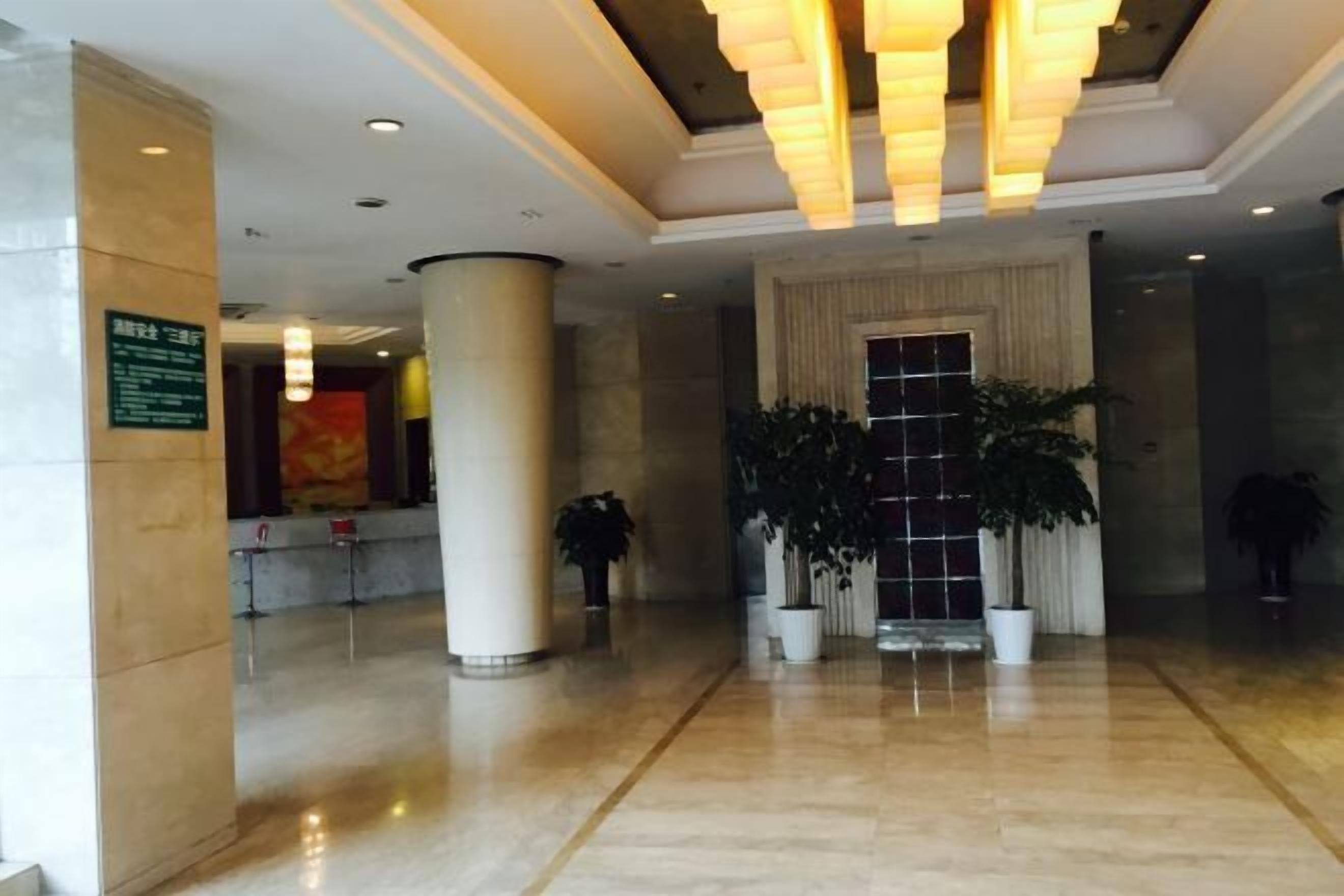A spacious lobby with a polished marble floor, large columns, and potted plants.
