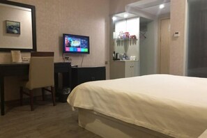 Une chambre d’hôtel comprenant un lit, un bureau avec une chaise, une télévision et une armoire.