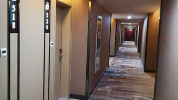 A hotel hallway with doors numbered 518 and 520, carpeted with a floral pattern, and a light fixture on the ceiling.