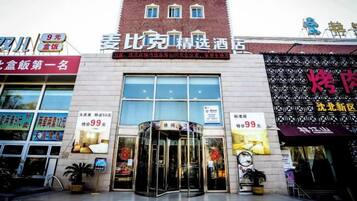 A hotel entrance with a revolving door, signage for a restaurant, and a storefront with a sign.