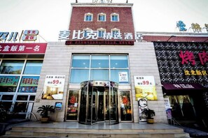 A hotel entrance with a revolving door, signage for a restaurant, and a storefront with a sign.