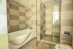 A bathroom with a bathtub, a glass shower enclosure, and a toilet.