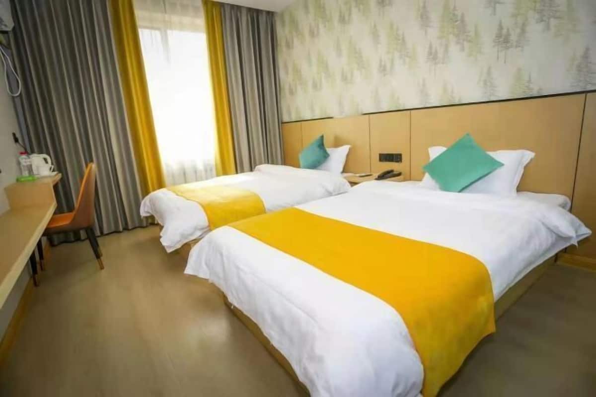 Hotellihuone, jossa on kaksi sänkyä, työpöytä ja tuoli.