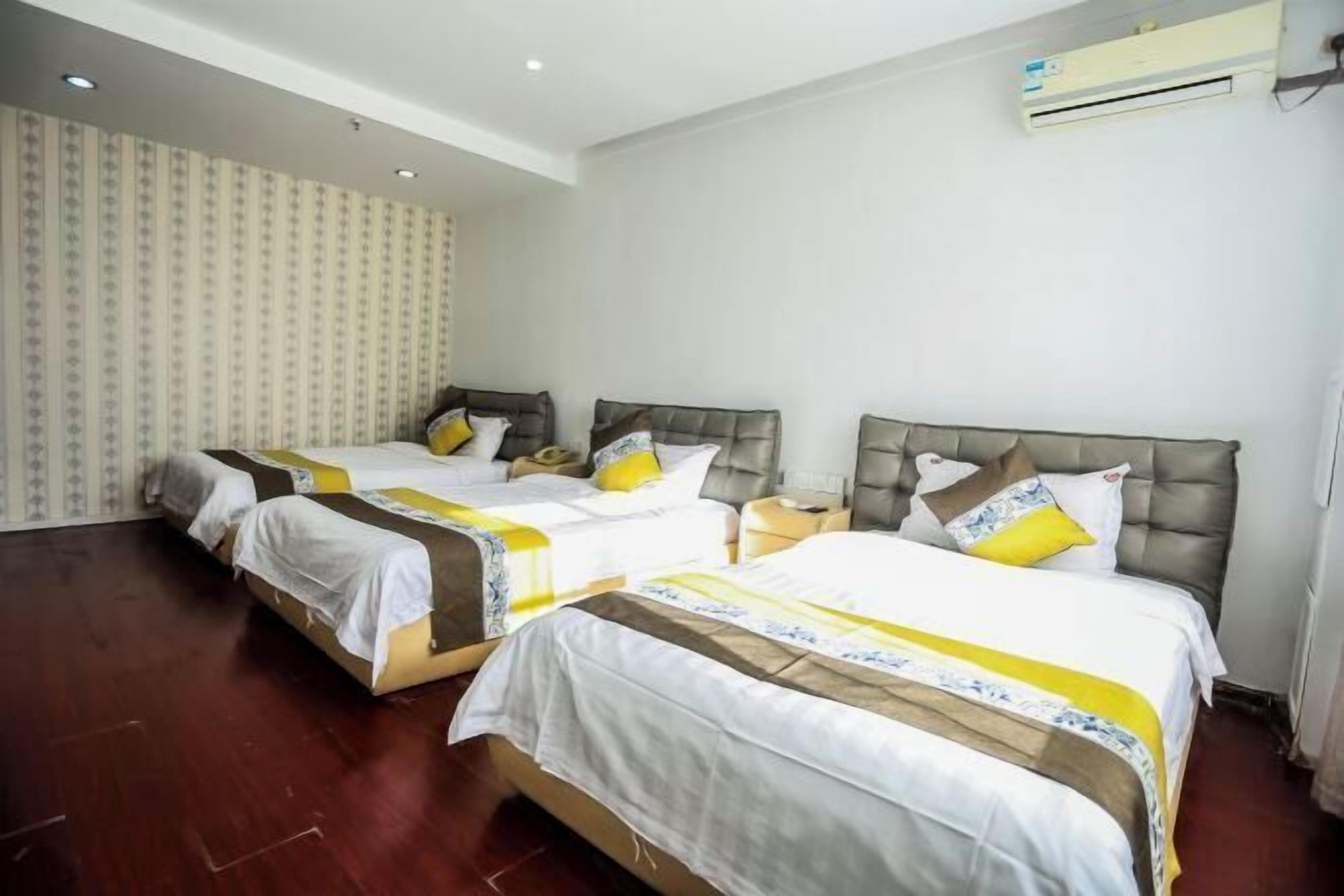 A hotel room with two beds, each with a headboard, bedside tables, and a neutral color scheme.