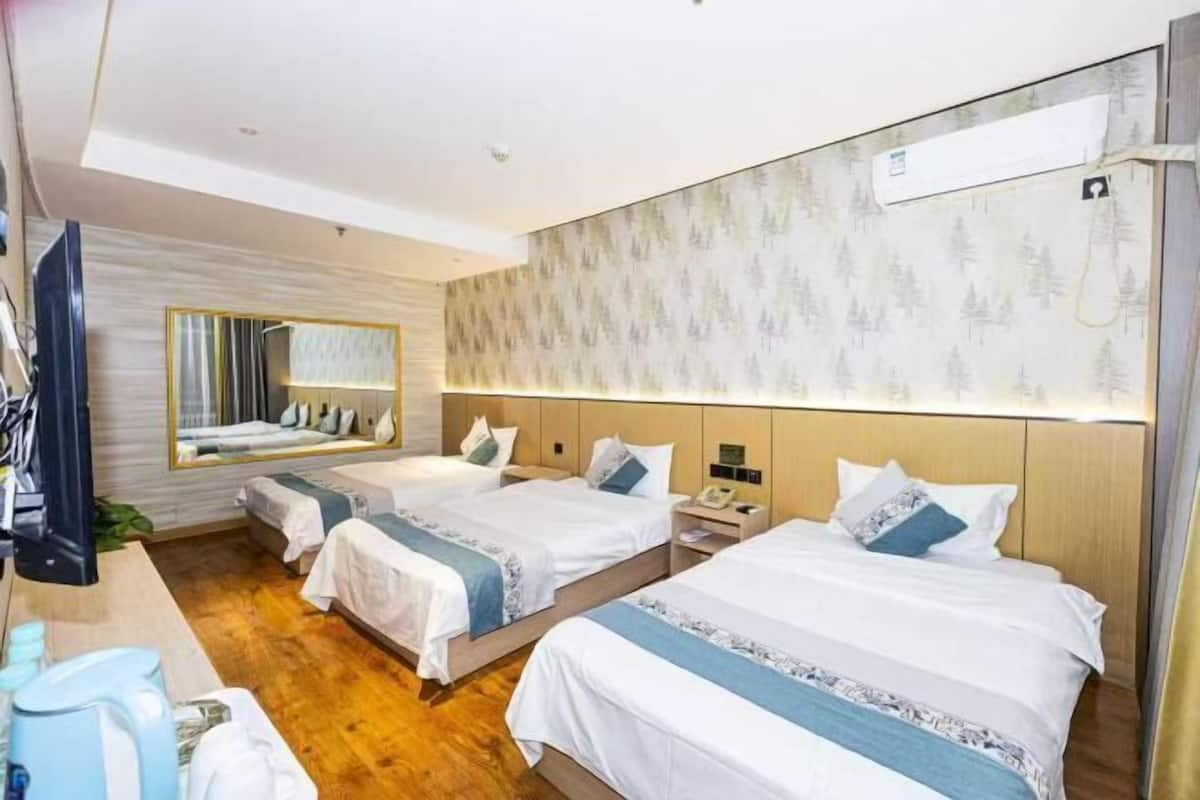 Hotellihuone, jossa on kaksi sänkyä, televisio, työpöytä, kahvinkeitin ja peili.