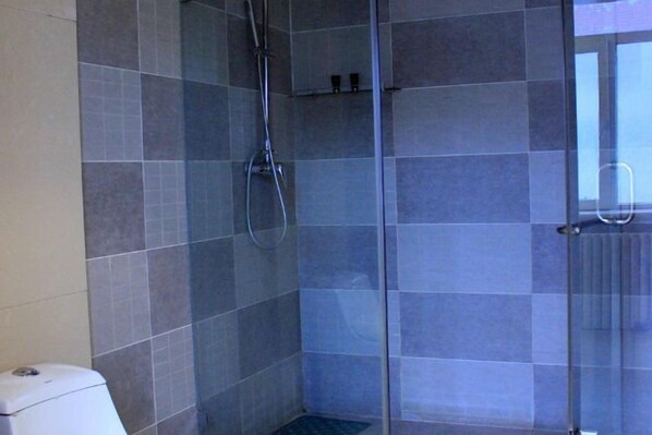 A shower area with a glass door, tiled walls, and a showerhead. - Maibike Select Hotel (Shenyang)
