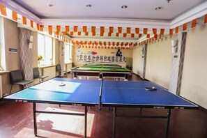 A room with two ping pong tables, a sofa, and a decorative banner.