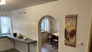 A kitchen with a tiled backsplash, a countertop with a toaster and a basket, and a dining area with a table and chairs. - HoLiDay HouSE Allgäu (Ottobeuren)