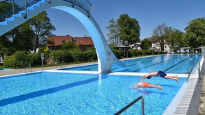A swimming pool with a diving platform and a person diving into the water. - HoLiDay HouSE Allgäu (Ottobeuren)