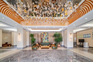 A spacious lobby with a marble floor, a seating area with sofas, and a decorative ceiling. - Xiniaogu Holiday Hotel (Yingjiang)