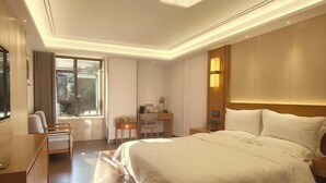 Quarto de hotel com uma cama grande, uma escrivaninha, uma cadeira e uma janela.