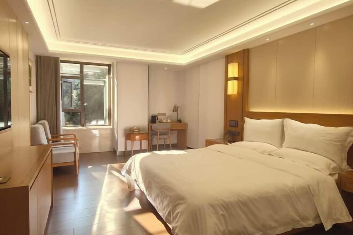 Ein Hotelzimmer mit einem großen Bett, einem Schreibtisch, einem Stuhl und einem Fenster.
