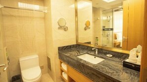 A bathroom with a marble sink, a toilet, a mirror, and a shower area.