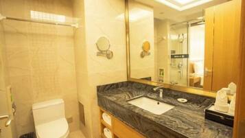 Un baño con lavamanos de mármol, inodoro, espejo y zona de ducha.