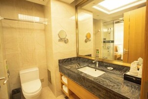 Un baño con lavamanos de mármol, inodoro, espejo y zona de ducha.