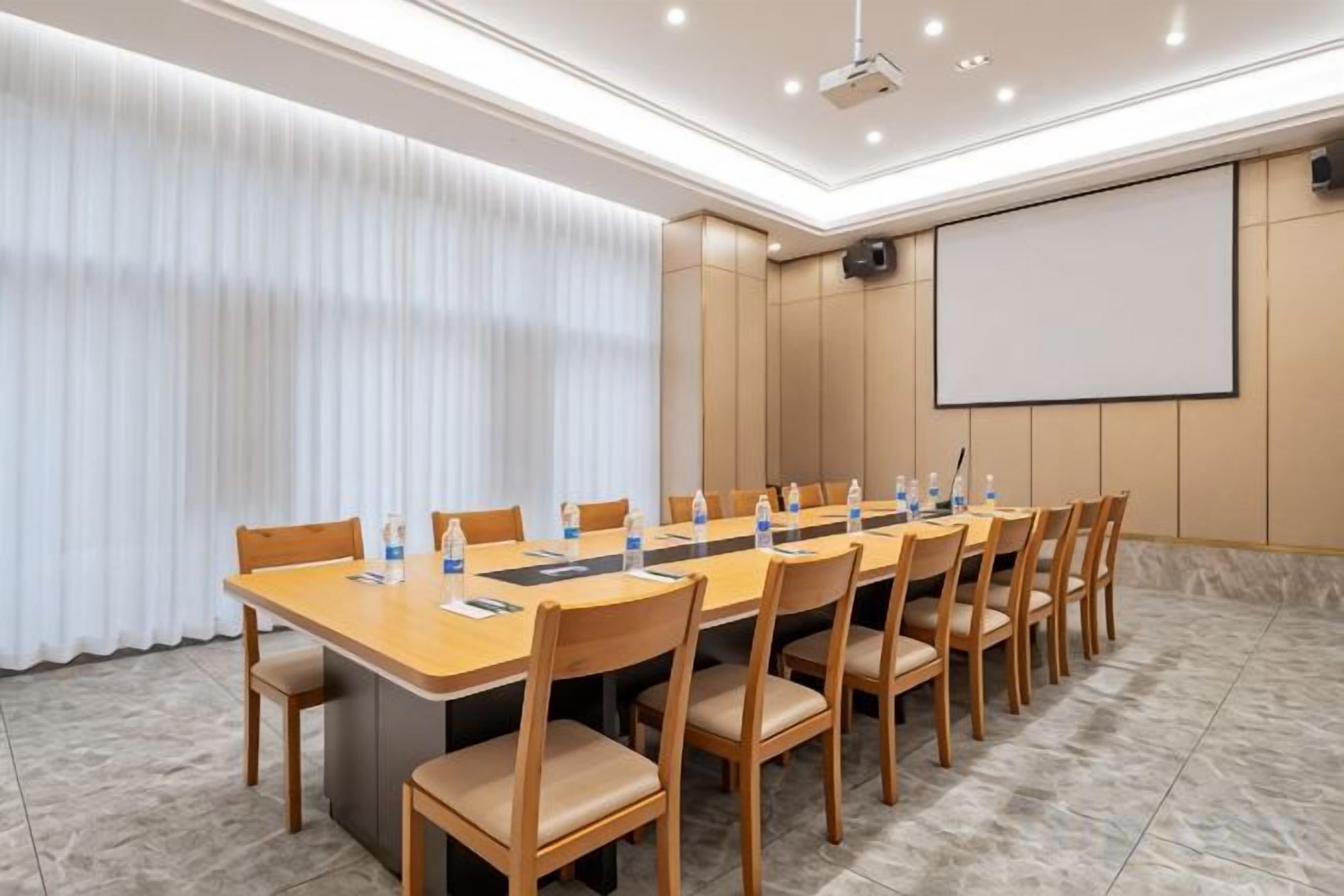 A conference room with a long table, chairs, a projector screen, and a whiteboard.
