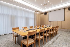 Een vergaderzaal met een lange tafel, stoelen, een projectorscherm en een whiteboard.