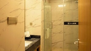 A bathroom with marble walls, a glass shower enclosure, and a sign in a foreign language.