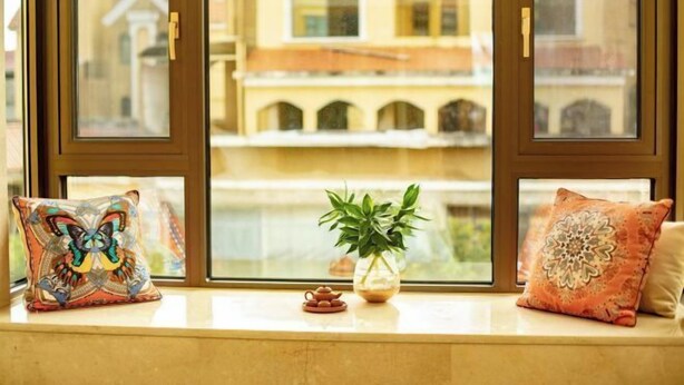 A window seat with decorative pillows, a small potted plant, and a teapot.