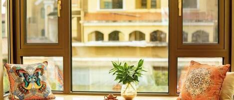 Asiento junto a la ventana con cojines decorativos, una planta pequeña en maceta y un hervidor de agua.