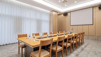 A conference room with a long table, chairs, a projector screen, and a whiteboard.