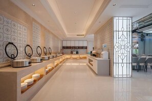 A modern hotel lobby with a long reception desk, a coffee station, and a seating area.