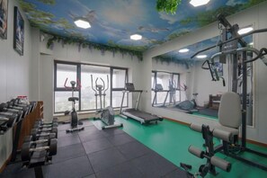 A gym with exercise equipment, a treadmill, and a mirror.