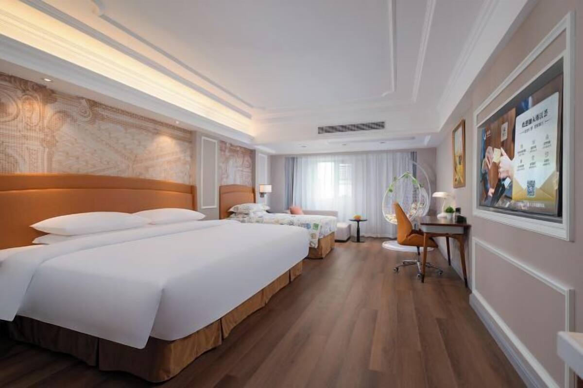 A hotel room with a large bed, a desk, and a chair.