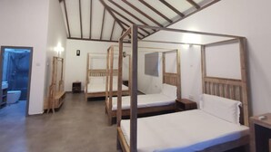 Quarto com quatro camas de dossel em madeira, piso de madeira e teto inclinado com vigas de madeira.