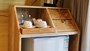 Uma cozinha compacta com geladeira embutida, cafeteira e bancada de madeira com copos e guardanapos.