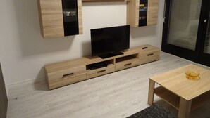 Ein modernes Wohnzimmer mit integriertem Fernseher, Holzschränken und einem kleinen Tisch mit dekorativer Schale.