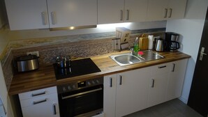 Eine moderne Küche mit weißen Schränken, einer Edelstahl-Spüle, einer Kaffeemaschine und einem Toaster.