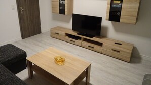 Ein modernes Wohnzimmer mit Flachbildfernseher auf einem Holz-TV-Möbel, Couchtisch und eingebauten Holzkabinetten mit Regalen.