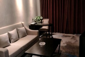 A living room with a sofa, a coffee table, a small table with a vase, and a red curtain. - Boyi Hotel (Mulei)