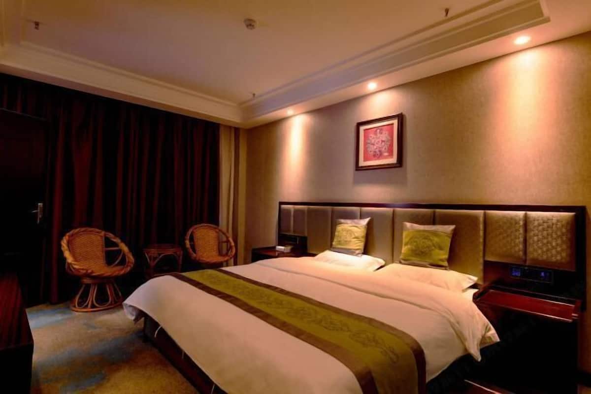 Ein Hotelzimmer mit einem großen Bett, zwei Nachttischen, einer Wanduhr und einem gerahmten Bild.