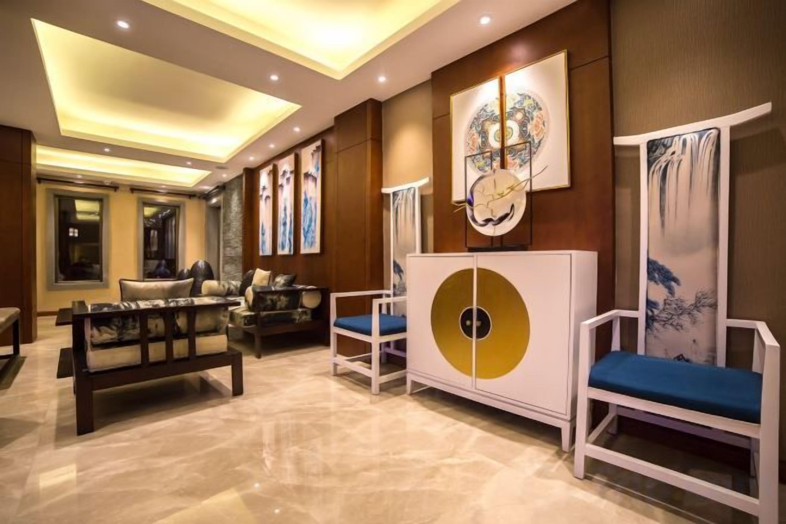 A hotel lobby with a seating area, a reception desk, and artwork on the walls.