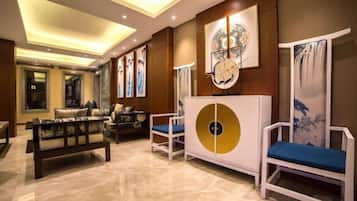 A hotel lobby with a seating area, a reception desk, and artwork on the walls.