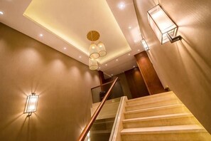 Una escalera con barandilla de madera y una lámpara colgante.