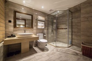Un baño moderno con lavamanos amplio, inodoro y ducha con mampara de vidrio.