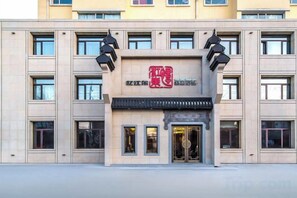 Un edificio con una entrada destacada, varias ventanas y un letrero con caracteres rojos.