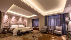 Una habitación de hotel moderna con una cama grande, un escritorio, dos sillas y un aplique de techo.