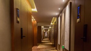 Un pasillo de hotel con puertas de madera, iluminación empotrada y suelo alfombrado.