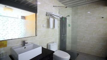 A bathroom with a white sink, toilet, and a glass-enclosed shower.