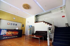 A reception area with a reception desk, a staircase, and a sofa. - Makeboat Hotel (Zhuhai Lovers Road Riyuebei Branch) (Zhuhai)