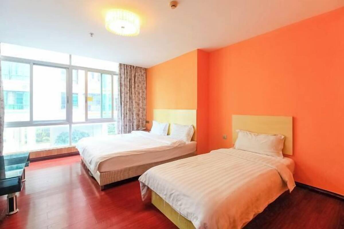 Habitación de hotel con dos camas, ventanas amplias y vistas al exterior.