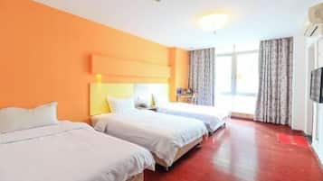 Habitación de hotel con dos camas, piso de madera, un ventanal grande con cortinas y un televisor de pantalla plana en la pared.