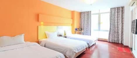 A hotel room with two beds, a wooden floor, a large window with curtains, and a flat-screen TV on the wall.