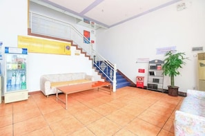A reception area with a staircase, a bench, a vending machine, and a potted plant. - Makeboat Hotel (Zhuhai Lovers Road Riyuebei Branch) (Zhuhai)