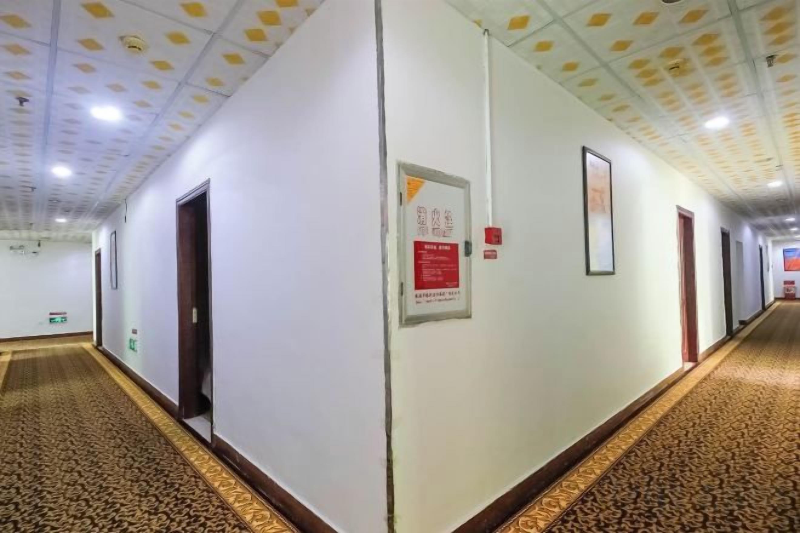 Um corredor com portas, piso coberto de carpete e teto com iluminação embutida.